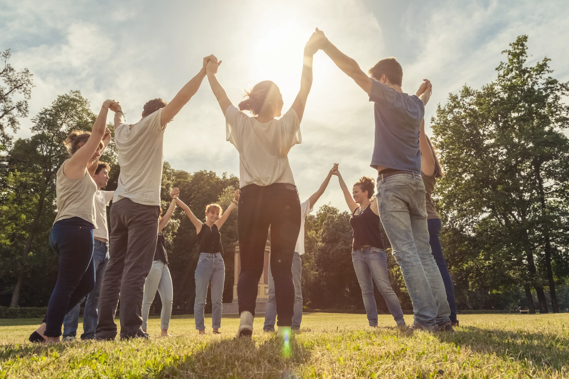 Group of ten friends at the park holding hands